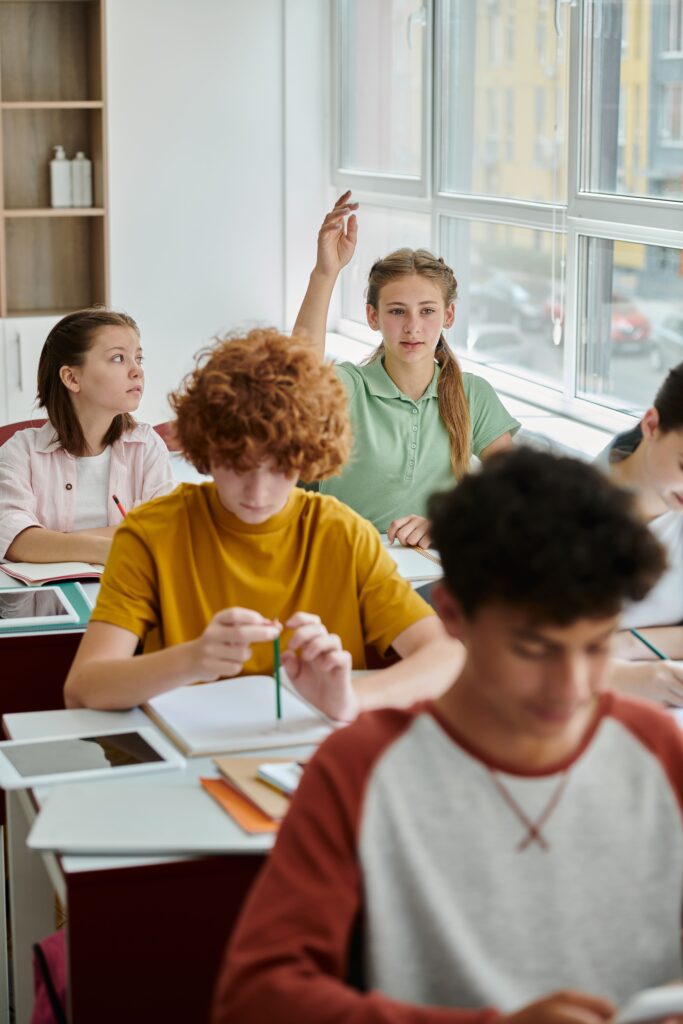 teenage-schoolgirl-raising-hand-and-talking-near-d-2024-11-11-20-33-13-utc